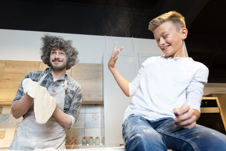 Father and son pre[aring pizza in kitchen. Relationship father and son