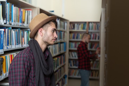 Handsome well-dressed man stands by bookshelves in a room with classic interior. Fashion.の写真素材