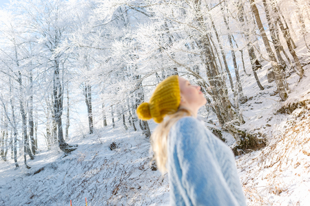 Beautiful young woman in her winter warm clothing. Happy woman having fun and enjoying winter in forest.の写真素材