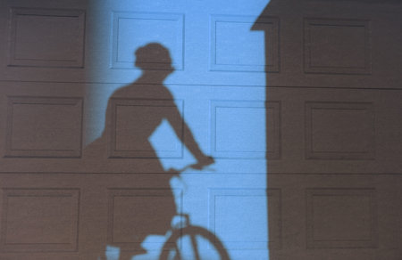 Shadow of a woman riding a bike on a textured wall. Two tonal image