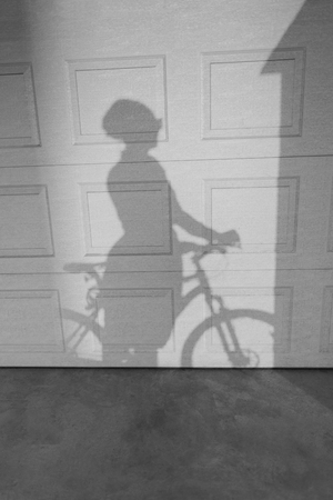 Shadow of a woman riding a bike on a textured wall. Two tonal imageの写真素材