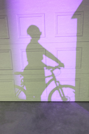 Shadow of a woman riding a bike on a textured wall. Two tonal imageの写真素材