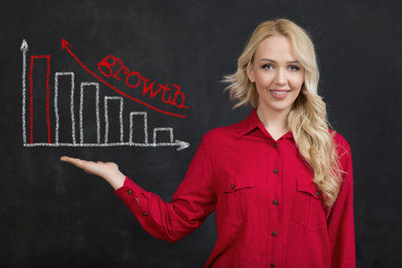 Beautiful business woman with graphical presentation showing the growth above hand on black...
