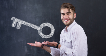 Real Estate Concept. Portrait of man in front of chalkboard with house keyの写真素材
