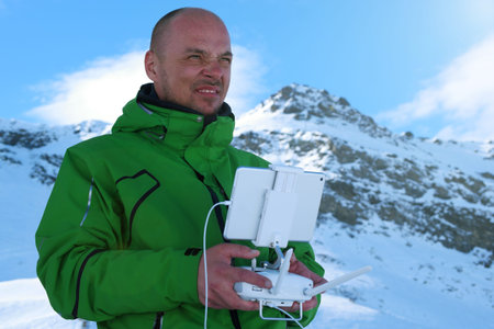 Man hands handling drone in winter Alpine landscape panorama