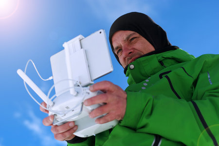 Man hands handling drone in winter against the blue sky background