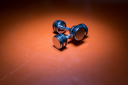 Photo of dumbells on a gym floor. Dumbells with centered light. Focus in center.の写真素材