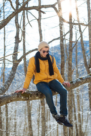 Hiker man with backpack and sleeping bag walking in the mountains in winter at sunset time. Enjoying the nature concept.の写真素材