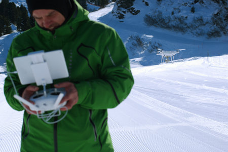 Man hands handling drone in winter Alpine landscape panorama
