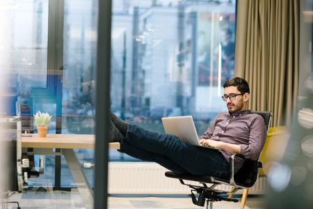 Full length side view of businessman using computer at desk in officeの写真素材