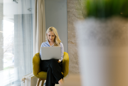 Portrait of a stunning fashionable model sitting in a chair. Business, elegant businesswoman. Interior, furniture.の写真素材