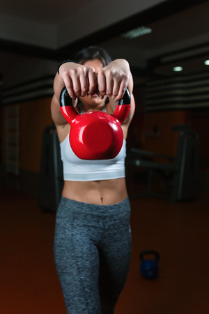 Attractive young athlete with muscular body exercising crossfit. Woman in sportswear doing crossfit workout with kettle bellの写真素材