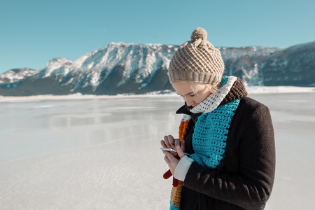 woman using smartphone on frozen lake in winter の写真素材