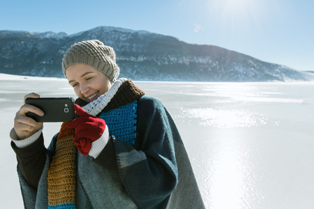 Pretty young female tourist takes selfie in winterの写真素材