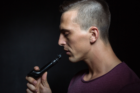 Man on black background vaping and releasing a cloud. の写真素材