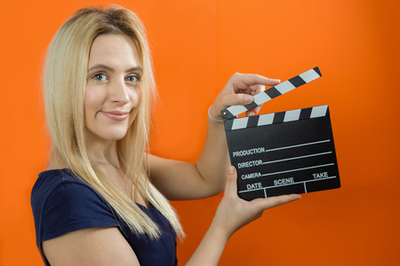 Young woman in action, holding clapperboard. Cinema conceptの写真素材