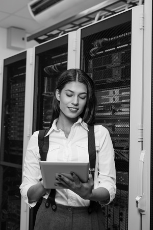 Technician using tablet pc while analysing server in large data centerの写真素材