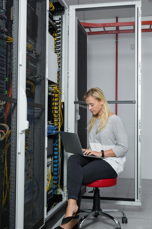 Portrait of technician working on laptop in server roomの写真素材
