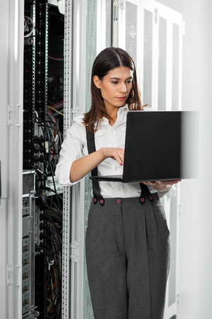 Portrait of technician working on laptop in server roomの写真素材