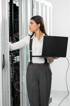 Portrait of technician working on laptop in server roomの写真素材