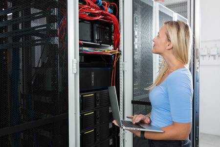 Portrait of technician working on laptop in server roomの写真素材