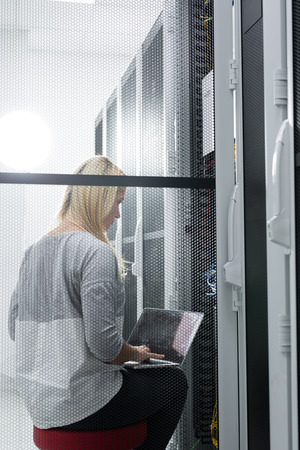 Portrait of technician working on laptop in server roomの写真素材