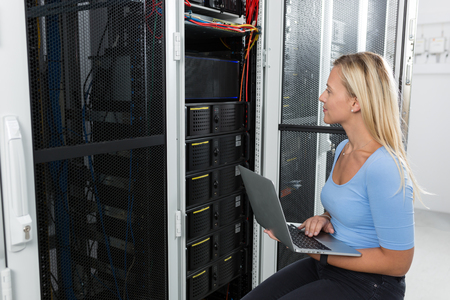 Portrait of technician working on laptop in server roomの写真素材