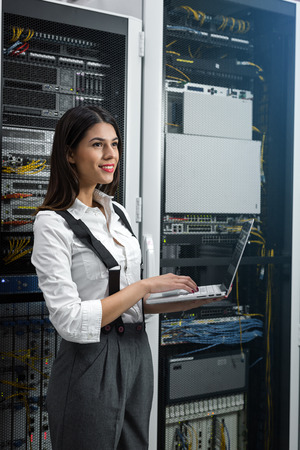 Portrait of technician working on laptop in server roomの写真素材