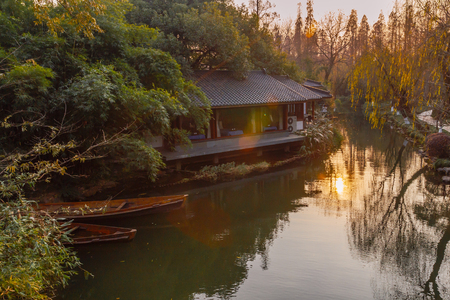 Traditional Chinese houses and boats by a river in a park in Hangzhou, Chinaのeditorial素材