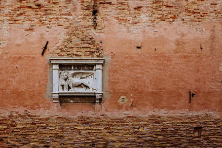 Sculpture of the Lion of Venice on old red brick wall in Venice, Italyの写真素材