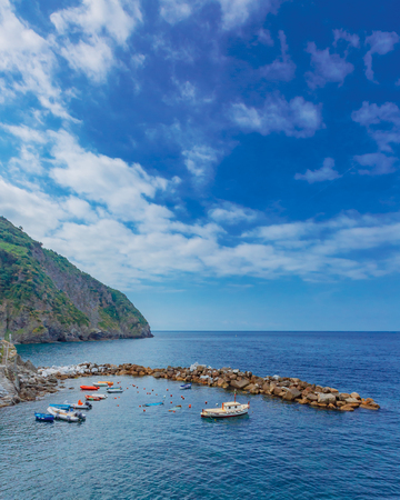 Boats by the port of Riomaggiore and view of the sea, in Cinque Terre, Italyの写真素材
