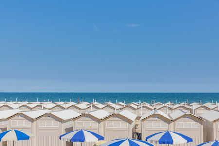 Huts and umbrellas on the beach of Lido in Venice, Italy, next to the sea, under blue skyのeditorial素材