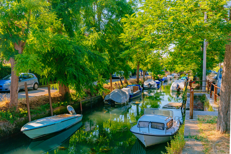 View of Canal and boats under trees in Lido of Venice, Italyのeditorial素材