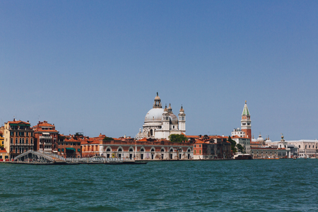 View of the dome of Santa Maria della Salute Church and St. Mark's Bell Tower over houses and canal in Venice, Italyの写真素材