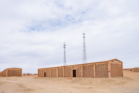 Brick houses and transmission towers in the gobi desert near the town of Yangguan, Gansu, Chinaのeditorial素材