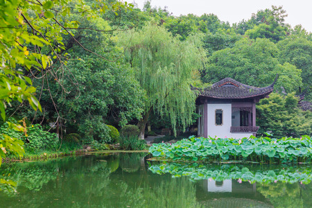 View of landscape with trees and Chinese house and reflections on water near West Lake, Hangzhou, Chinaの写真素材