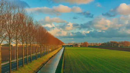 View of fields under sky and clouds in the dutch countryside near Rotterdam, the Netherlandsの写真素材
