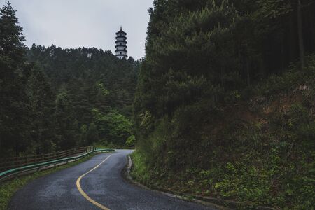 Roads between mountain ridges with pagoda on top of mountain with trees on Mingyue Mountain, Jiangxi, Chinaの写真素材