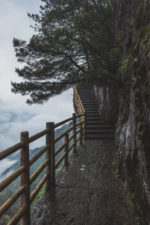 Gallery road on cliff next to deep valley covered in clouds, on top of Mingyue Mountain, Jiangxi,...