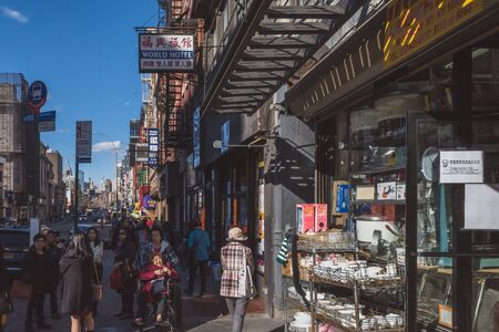 April 10, 2019 - New York City, USA: Pedestrian walking down street passing shops in Manhattan Chinatownのeditorial素材
