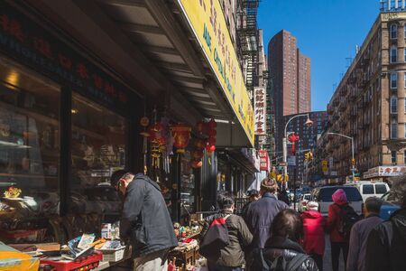 April 16, 2019 - New York City, USA: Pedestrian walking down street passing shops in Manhattan Chinatownのeditorial素材
