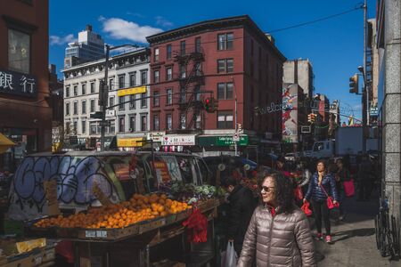 April 10, 2019 - New York City, USA: Pedestrians walking past fruit vendors in street of Manhattan Chinatownのeditorial素材