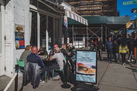 April 10, 2019 - New York City, USA: People eating at outdoor seating of a restaurant in lower Manhattanのeditorial素材
