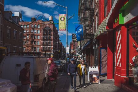 April 10, 2019 - New York City, USA: Pedestrian walking down street passing shops in Manhattan Chinatownのeditorial素材