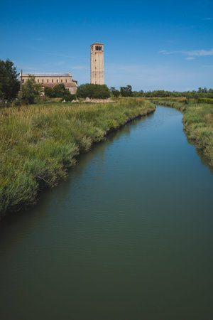 Cathedral of Santa Maria Assunta and bell tower by river on island of Torcello, in Venice, Italy