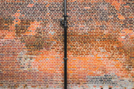 Background texture of brown brick wall with black rain pipeの写真素材