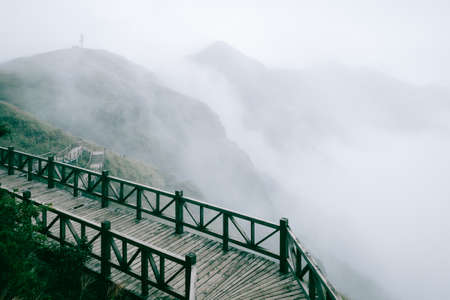 Wooden plank path between meadow covered in fog on top of Wugong Mountain (Wugongshan) in Jiangxi, Chinaの写真素材