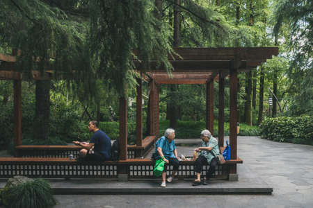 Hangzhou, Zhejiang, China - 11 August 2019: Locals relaxing and eating at a gazebo among trees near West Lakeのeditorial素材