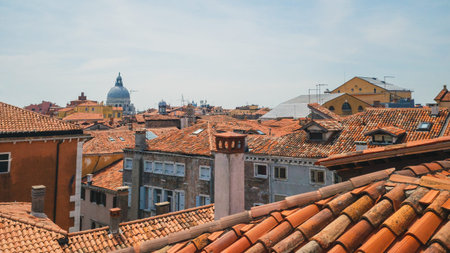 View of dome of Basilica of Santa Maria della Salute over traditional Venetian houses under blue sky...