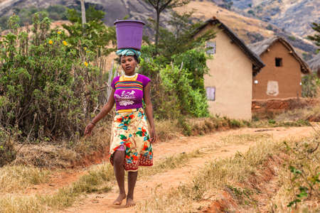 African Girl carries heavy basket on head.のeditorial素材